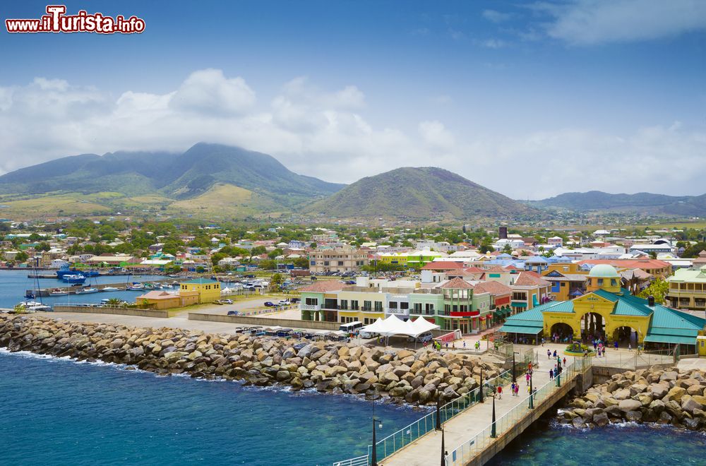 Immagine Porto Zante nella città di Basseterre, St. Kitts and Nevis, Indie Occidentali. Le belle montagne sullo sfondo fanno da scenario al porto e alle graziose case colorate.