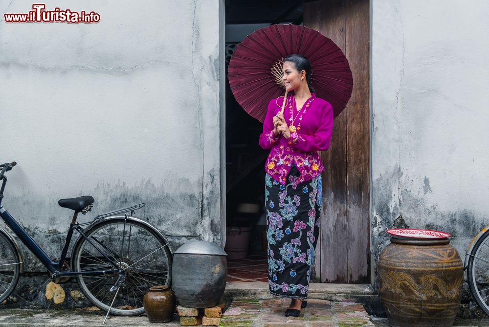 Immagine Provincia di Ranong, Thailandia: una giovane ragazza indossa un abito Nyonya e tiene in mano un ombrello di carta.