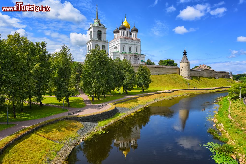 Immagine Pskov, Russia: la torre di avvistamento, le mura e la cupola d'oro della cattedrale della Trinità con i riflessi sull'acqua del fiume Velikaja.