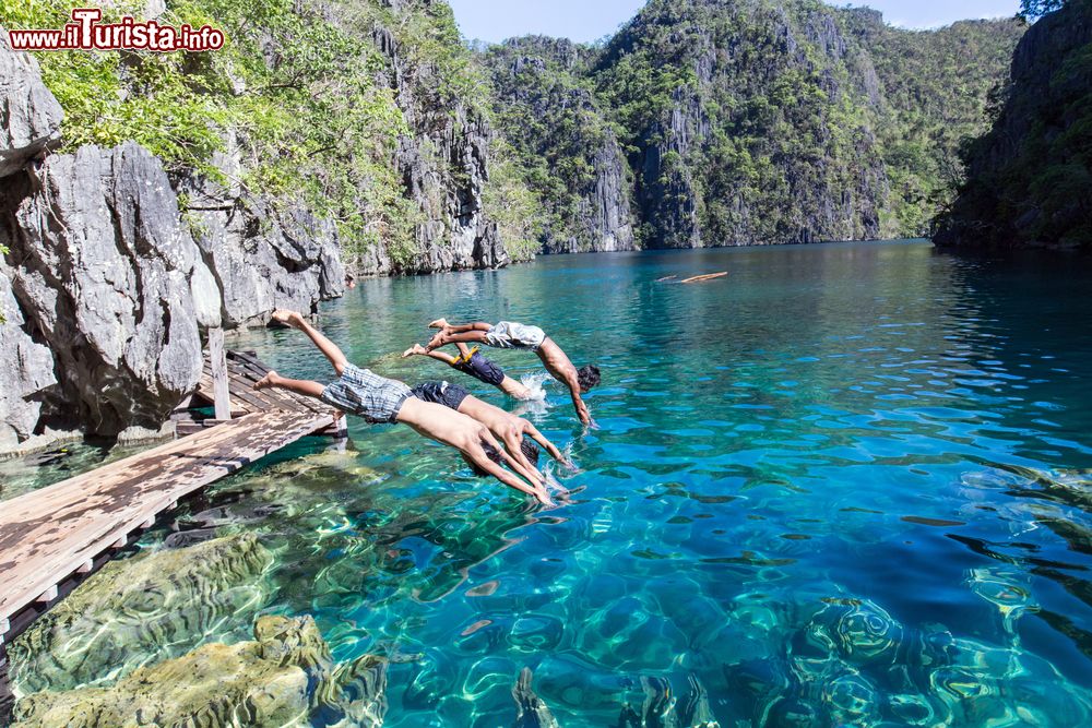 Immagine Quattro giovani si tuffano nelle acque del lago Kayangan a Palawan, Filippine. Questo bacino d'acqua è considerato uno dei più limpidi di tutta l'Asia nonchè uno dei luoghi più fotografati delle Filippine.