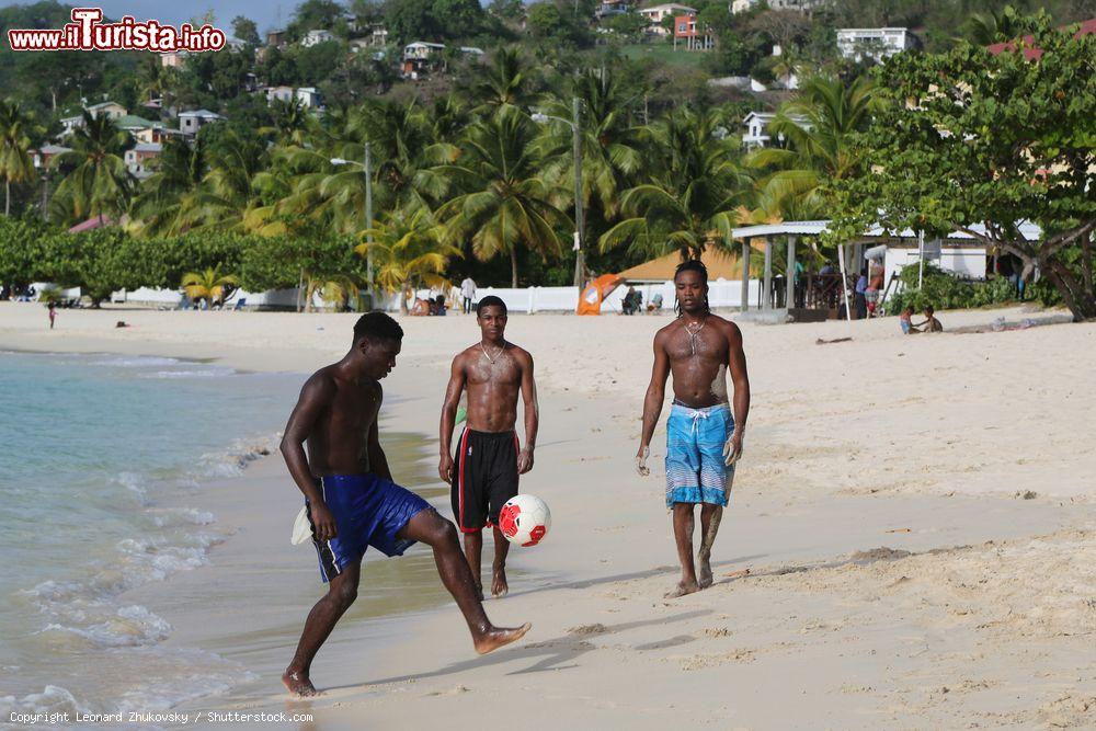 Immagine Ragazzi giocano a pallone a Grand Anse Beach, Grenada, in una giornata di sole.  A circa 5 km a sud di St.Georges si trova la spiaggia più famosa e lunga (3 km) della cittadina: Grand Anse Beach è una lingua di sabbia bianca e fine immersa nel mare caraibico - © Leonard Zhukovsky / Shutterstock.com