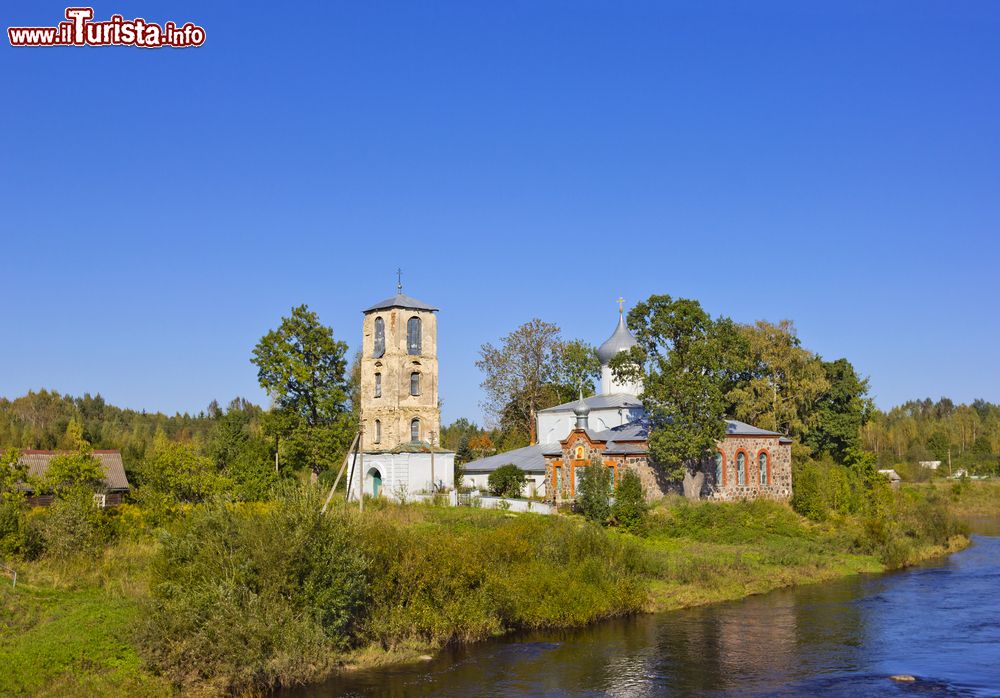 Immagine Regione di Pskov: un'antica chiesa ortodossa, in pietra e calce, con il campanile sulle sponde del fiume, Russia.