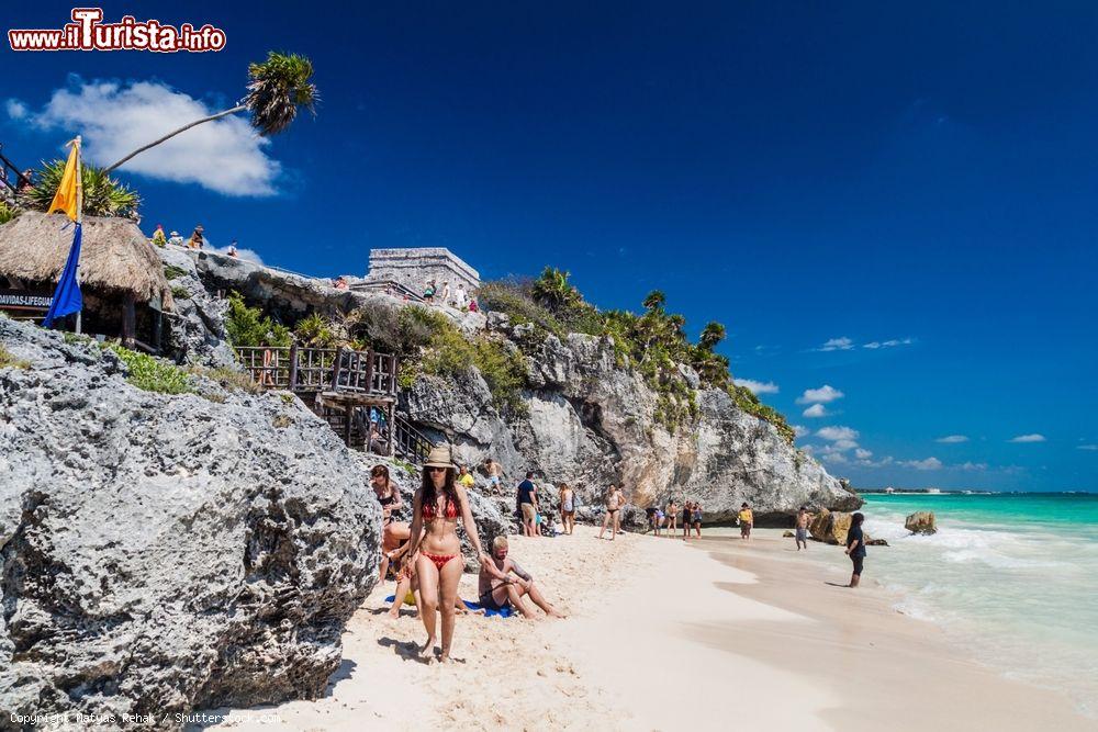 Immagine Relax in spiaggia sotto le rovine dell'antica città di Tulum, Messico. L'antico edificio in pietra chiamato Castillo è arroccato su una scogliera e domina dall'alto la spiaggia di sabbia dorata e il mare cristallino - © Matyas Rehak / Shutterstock.com