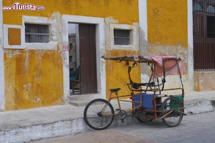 Immagine Scorcio panoramico di Izamal, Messico. Questa località dello Yucatan è famosa come "La città gialla" perchè buona parte dei suoi edifici sono dipinti con questa tonalità. Nell'immagine, un simpatico taxi bicicletta con cui locali e turisti si spostano comodamente - © doromonic / Shutterstock.com