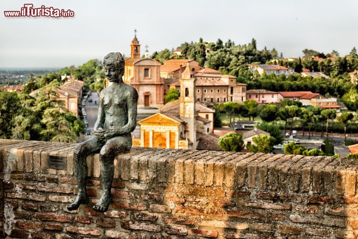 Immagine Scultura a Longiano, Emilia Romagna, Italia. Una bella opera scultorea che raffigura un ragazzo seduto sulle mura del borgo medievale - © GoneWithTheWind / Shutterstock.com