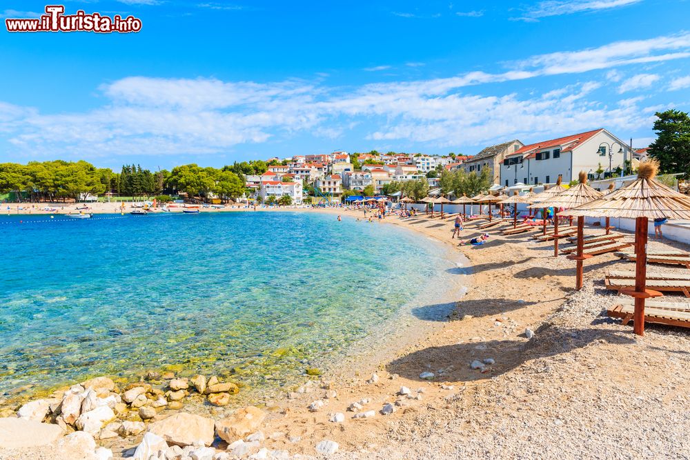 Immagine Sdraio e ombrelloni su una spiaggia dell'antica città di Primosten, Croazia. Questa splendida destinazione turistica della costa croata ospita qualcosa come 20 chilometri di spiaggia, per lo più ciottoli e in parte roccia.