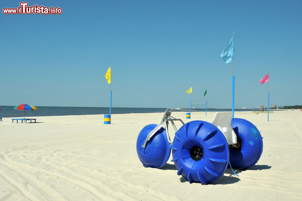 Immagine Sdraio, ombrelloni e un grande triciclo sulla spiaggia di Biloxi, Mississipi, Stati Uniti. Un tratto del litorale di sabbia bianca e soffice della cittadina situata nella contea di Harrison.