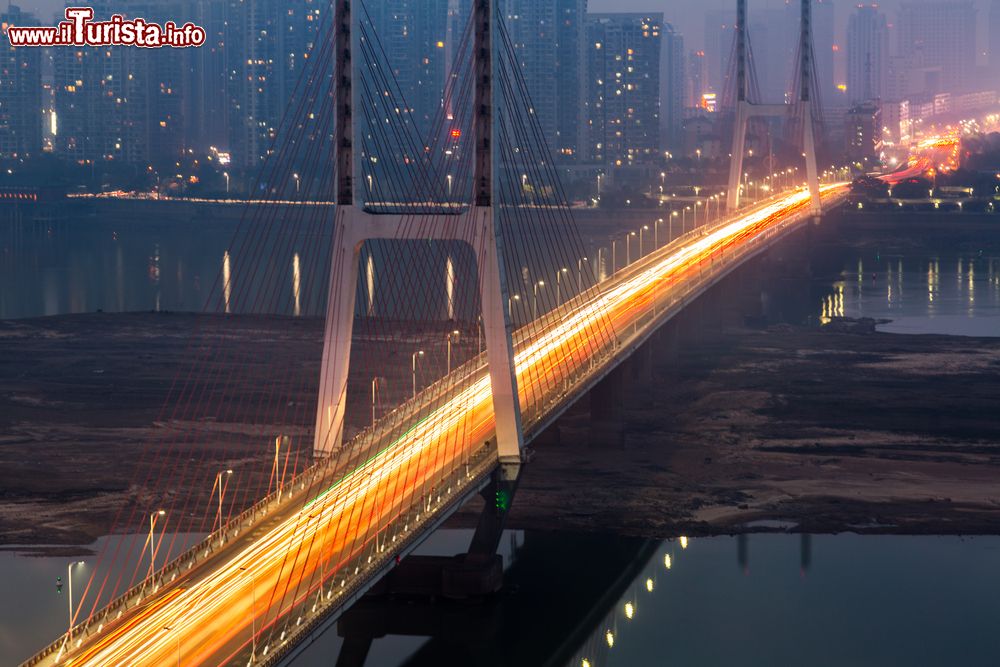 Immagine Skyline di un ponte di Nanchang, Cina, by night. Sorge lungo il corso inferiore dei fiumi Ganjiang e Wuhe e confina con il lago Poyang, il più grande d'acqua dolce del paese.