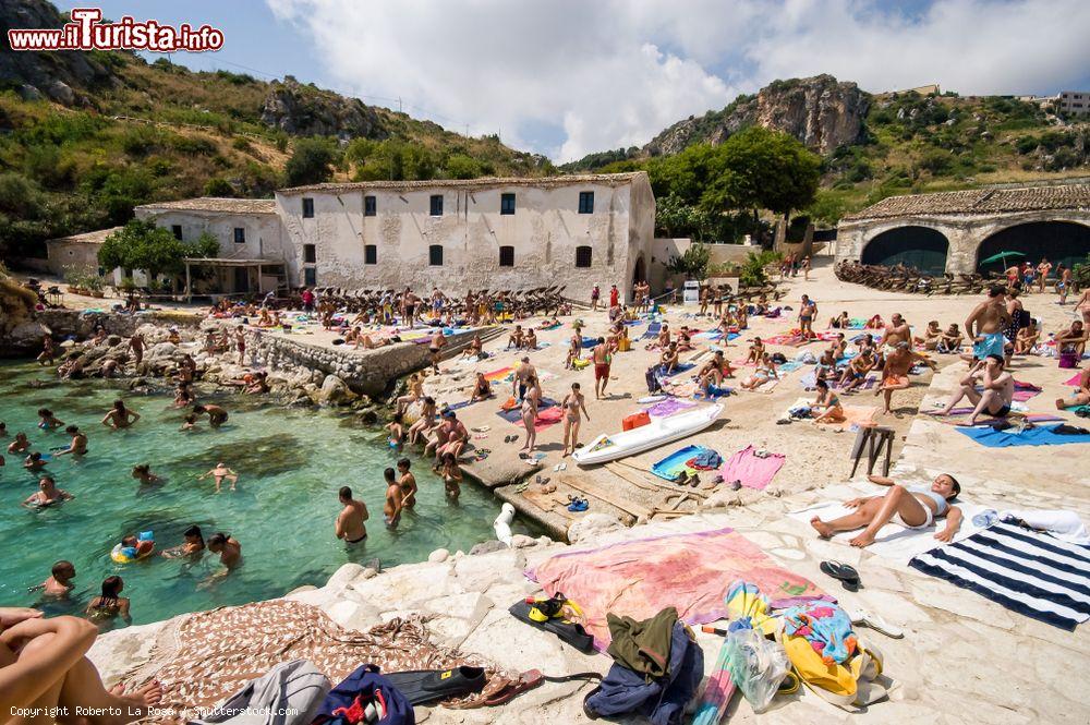 Immagine Spiaggia affollata alla vecchia Tonnara di Scopello, provincia di Trapani (Sicilia). Un tempo tenuta medievale destinata alla pesca del tonno, questa struttura è oggi un museo oltre che una locanda disponibile per eventi - © Roberto La Rosa / Shutterstock.com