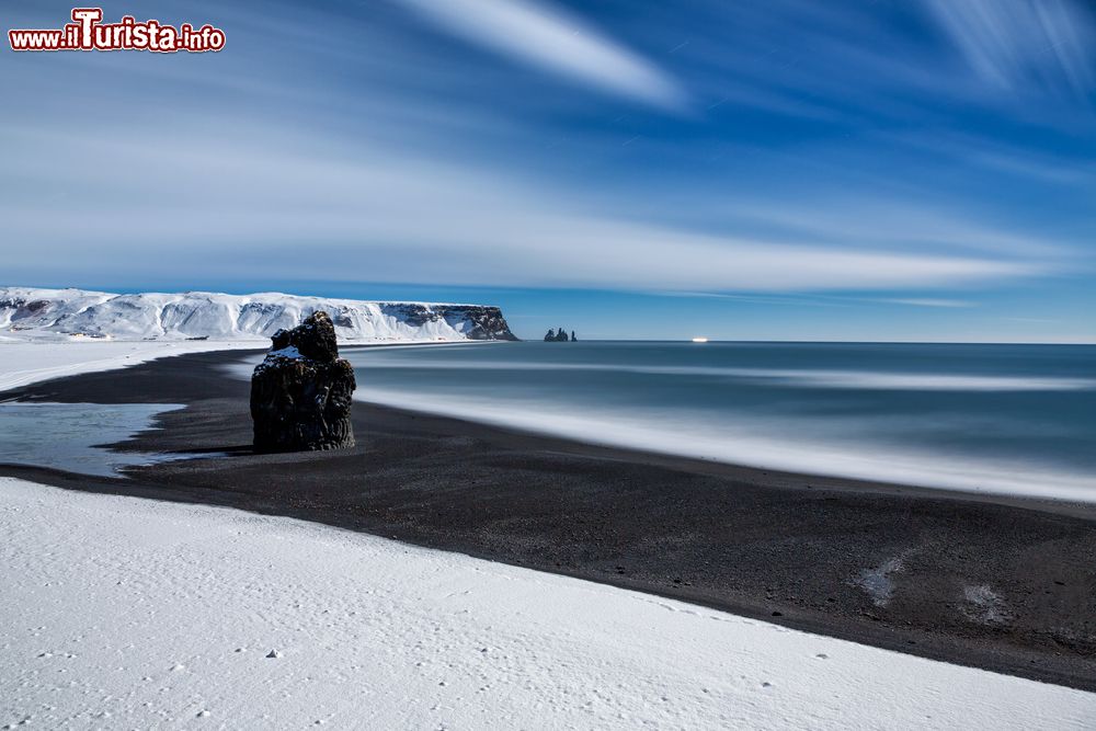 Immagine Una splendida immagine dei faraglioni di Reynisdrangar sulla spiaggia di Reynisfjara, Islanda. La luce della luna e l'aurora, complice anche la neve, rendono il paesaggio di questo tratto di costa vicino a Vik i Myrdal davvero unico.