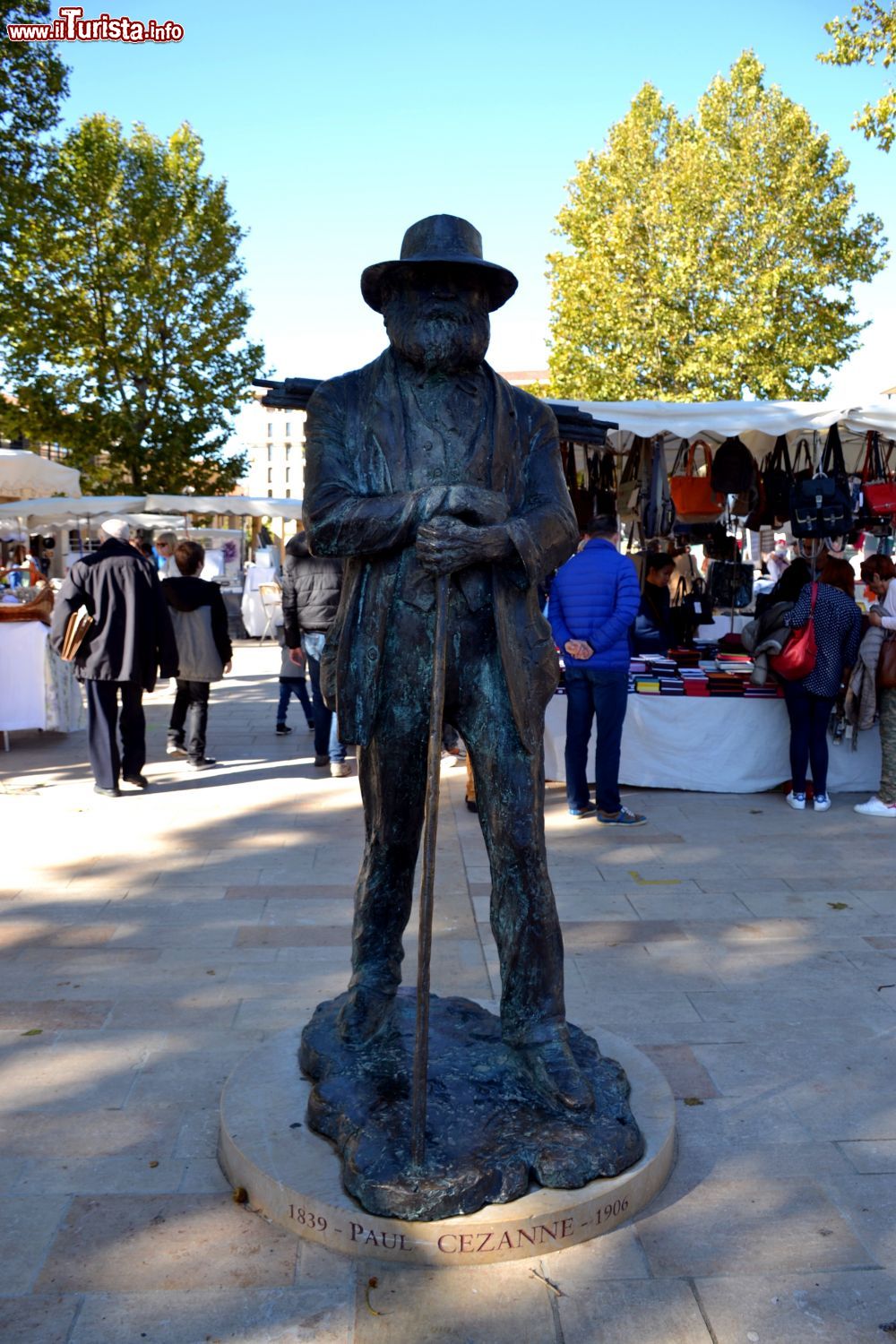 Immagine La statua di Cézanne tra le bancarelle del mercato che circonda la Fontaine de la Rotonde ad Aix-en-Provence (Francia).