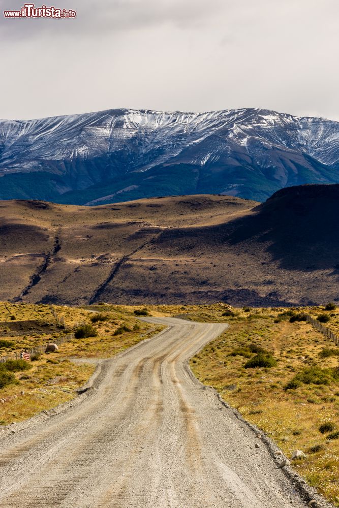 Immagine Strada sterrata in pendenza vista dal parabrezza di un autobus in Patagonia, Puerto Natales, Cile. Questa località cilena è situata su una riva del Canal Senoret e offre panorami desertici e montani.