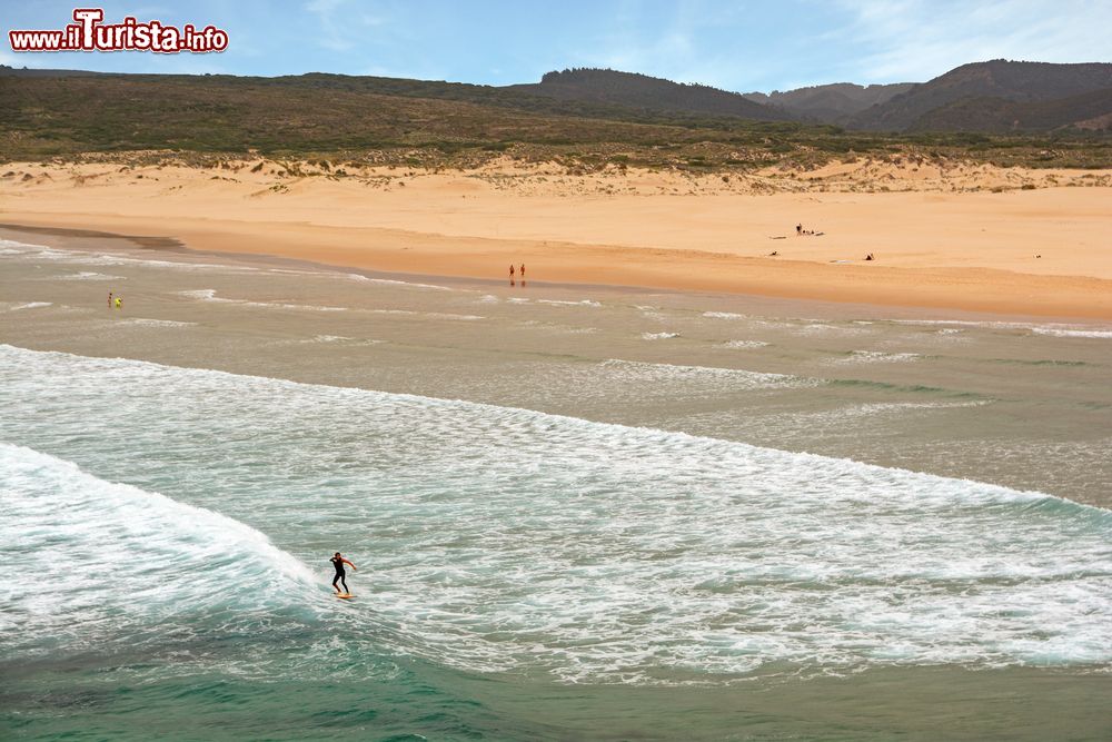 Immagine Surfer con la tavola a Praia da Bordeira, Carrapateira, Algarve. Grazioso e tranquillo villaggio composto da poche case, Carrapateira è una vera e propria mecca per gli appassionati del surf.