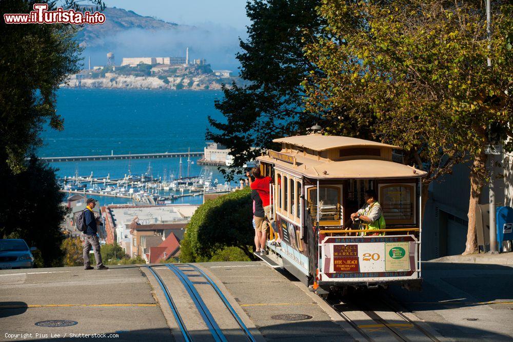 Immagine Turisti sul celebre tram a San Francisco, California, in una giornata di sole. Dalla cima di Hyde Street si gode un'impareggiabile vista sulla baia e la prigione di Alcatraz - © Pius Lee / Shutterstock.com