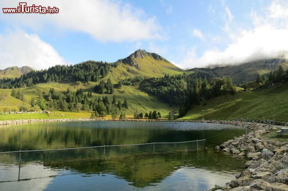 Immagine Un laghetto alpino nel borgo di Stoos, Svizzera. In questo territorio escursioni, passeggiate e itinerari escursionistici attendono gli appassionati di montagna nei mesi estivi e invernali.