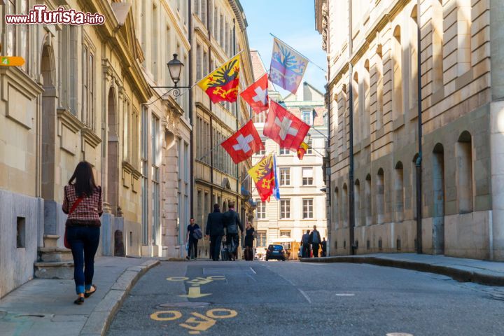 Immagine Un suggestivo scorcio panoramico di Rue de l'Hotel-de-Ville, nella vecchia città di Ginevra, con bandiere e gente in strada - © Michal Ludwiczak / Shutterstock.com 