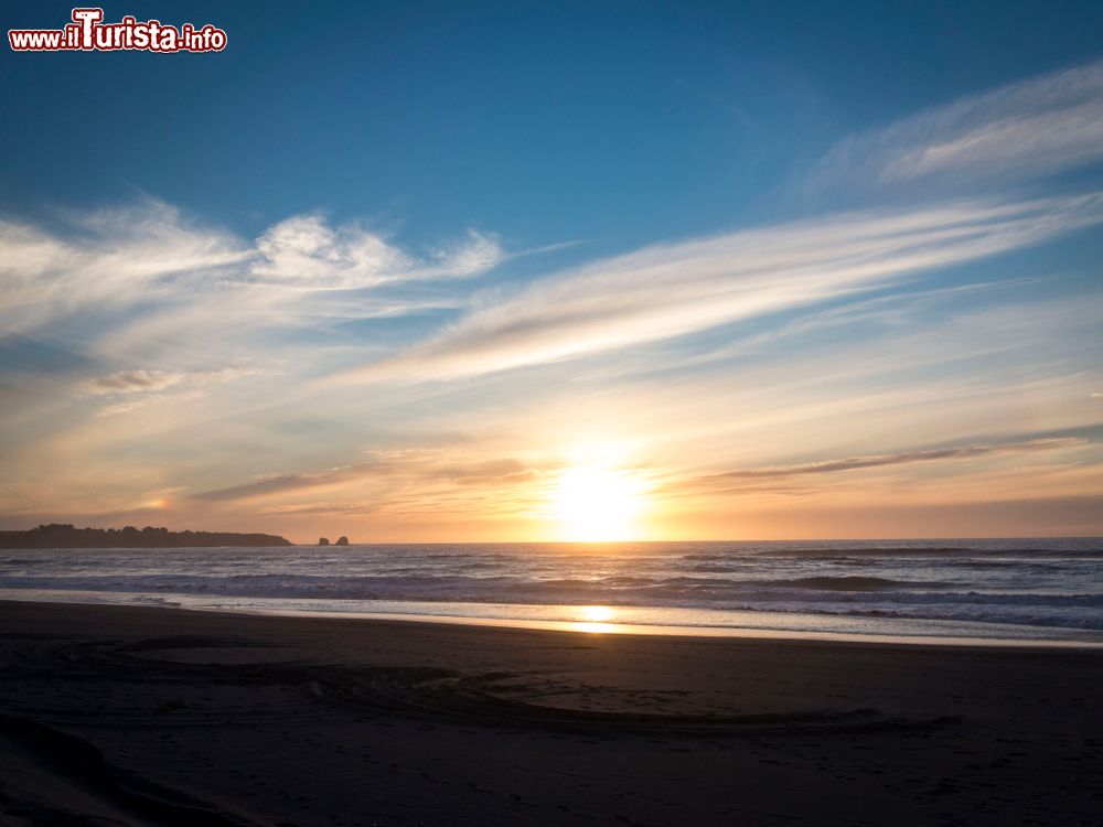 Immagine Un suggestivo tramonto a Pichilemu visto da Playa Hermosa, Cile. Le sfumature del cielo si riflettono nell'acqua del mare.