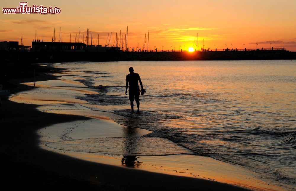 Immagine Un uomo passeggia al tramonto sulla spiaggia di Cattolica, Emilia Romagna.