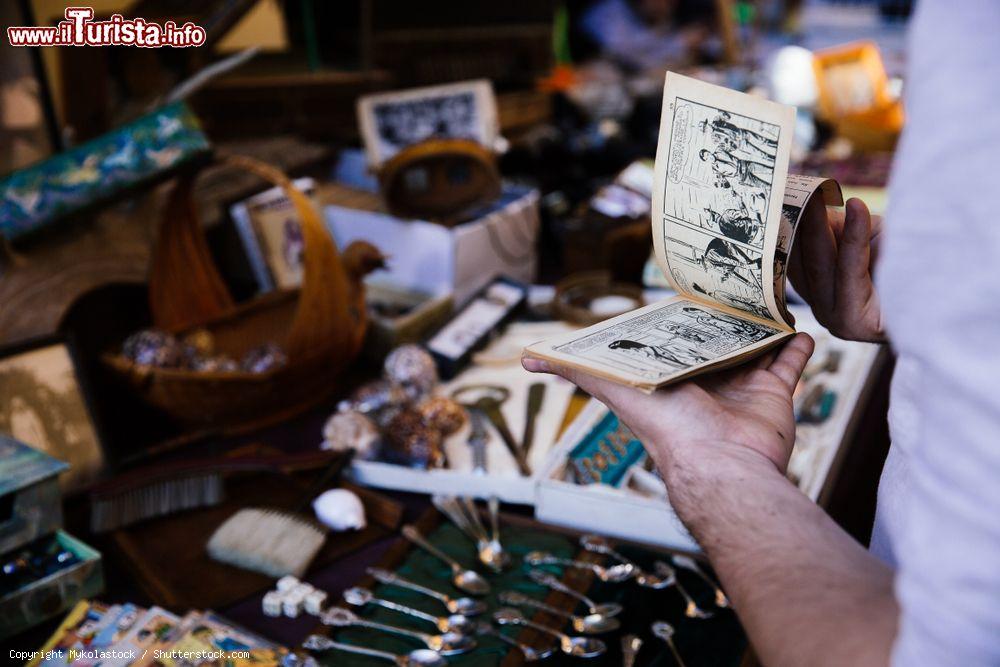 Immagine Un uomo sfoglia un libretto comico al mercato delle pulci a Barga, Toscana - © Mykolastock / Shutterstock.com