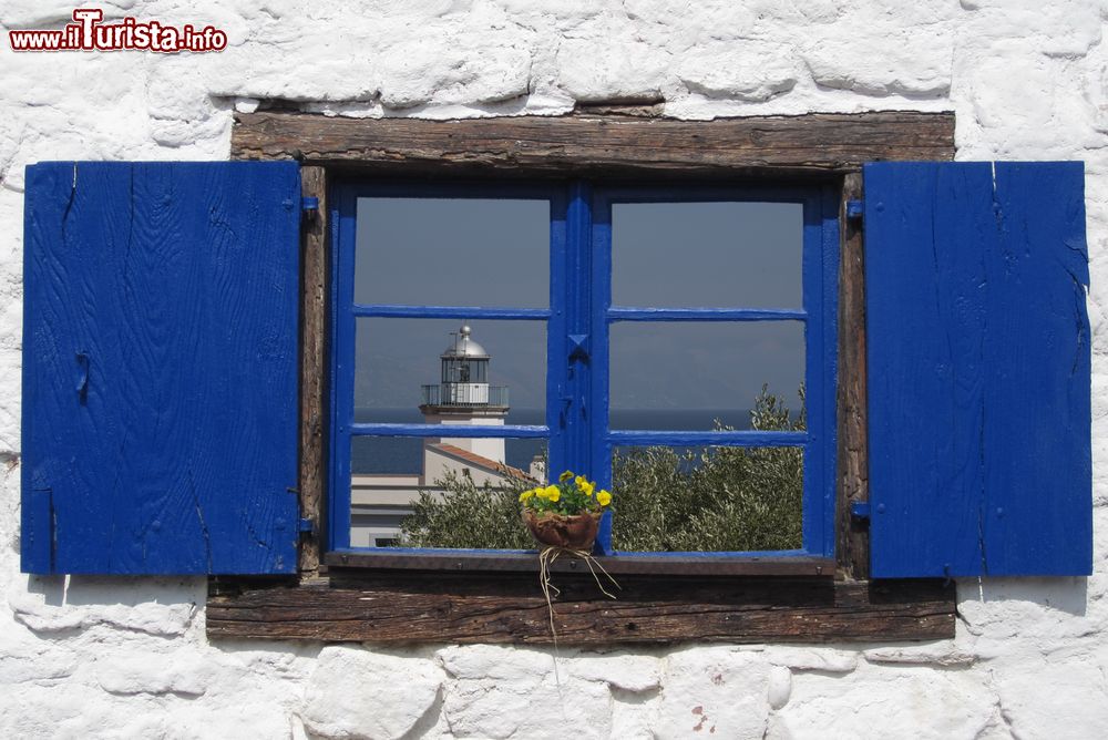 Immagine Una bella immagine del faro di Scario che si rispecchia in una finestra del borgo, Campania.