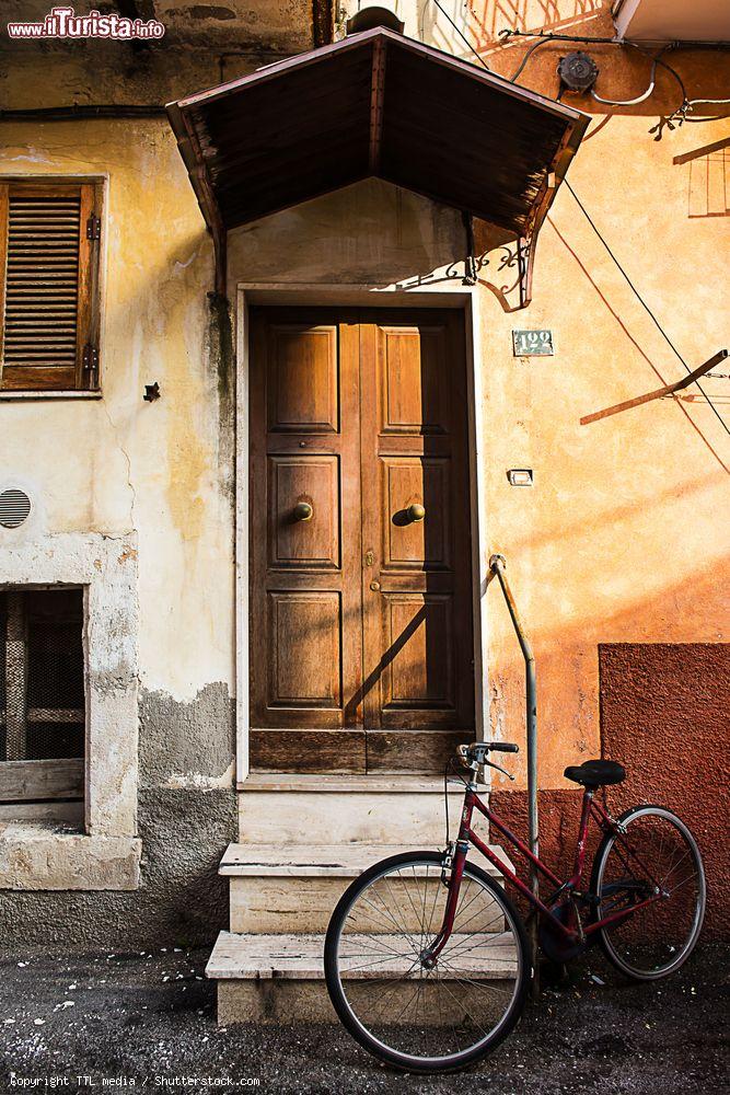 Immagine Una bicicletta davanti al portone d'ingresso di una casa a Popoli, Abruzzo. Una suggestiva immagine di vita quotidiana fotografata con la calda luce del tramonto - © TTL media / Shutterstock.com