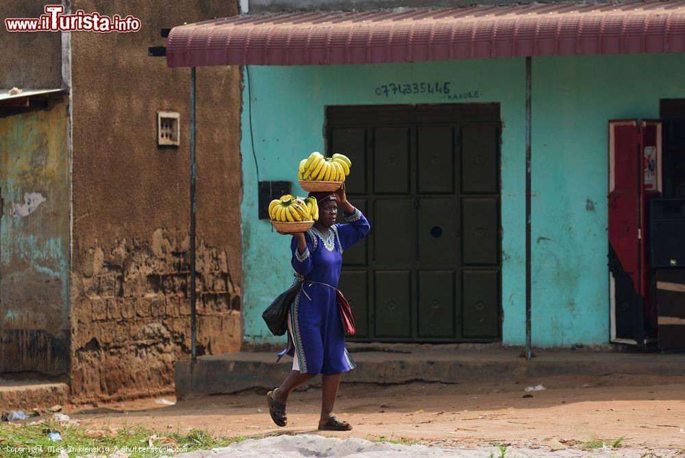 Immagine Una donna trasporta banane in una baraccopoli di Kampala, Uganda. Quasi il 40% degli abitanti di questi luoghi ha un reddito mensile inferiore a 1 dollaro - © Oleg Znamenskiy / Shutterstock.com