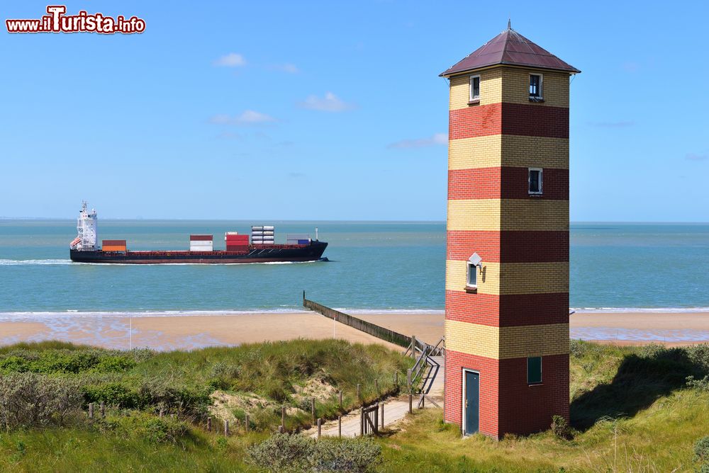 Immagine Una nave cargo nelle acque davanti alla costa di Vlissingen, Olanda. In primo piano, un faro a strisce.