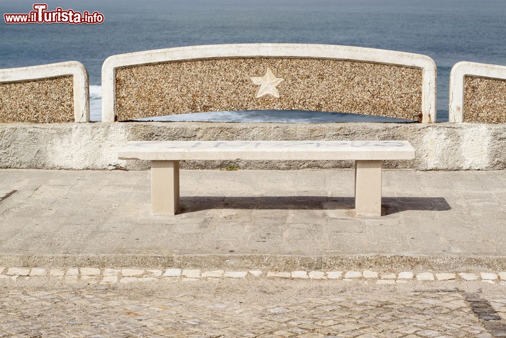 Immagine Una panchina lungo l'oceano a Ericeira, Portogallo. Dalla passeggiata che fiancheggia il litorale è possibile ammirare le acrobazie dei surfisti in azione.