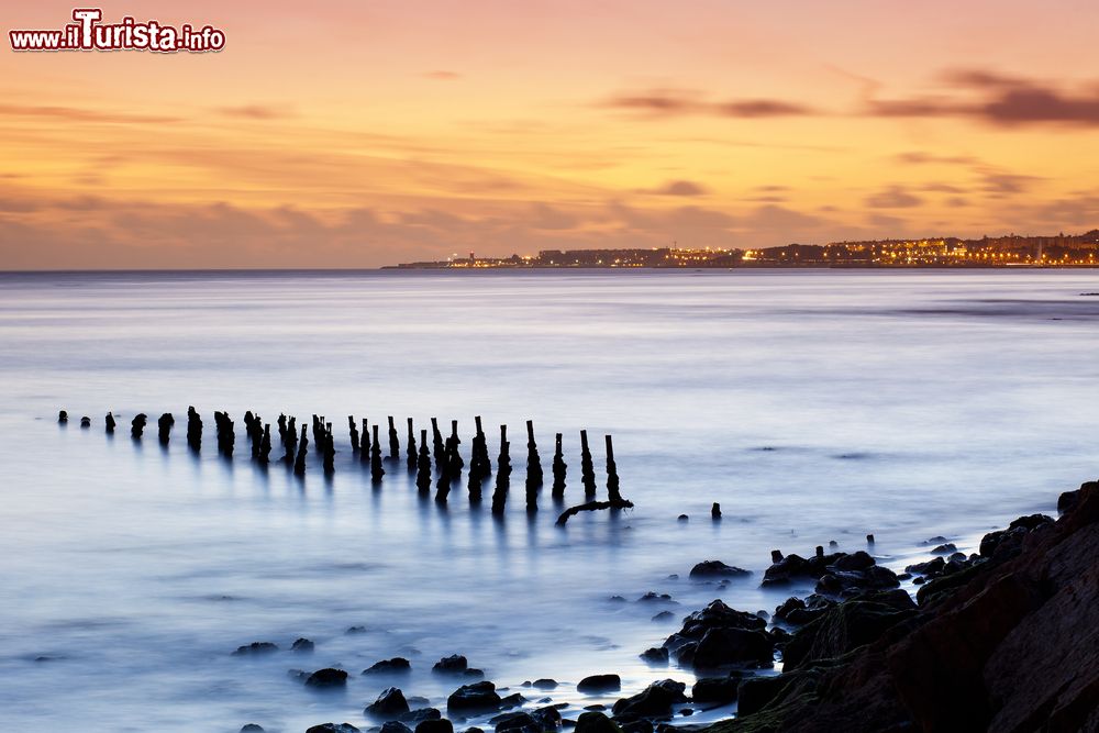 Immagine Una suggestiva immagine di Cruz Quebrada a Oeiras, Portogallo. I colori del tramonto tingono di mille sfumature il cielo sopra la città di Oeiras.