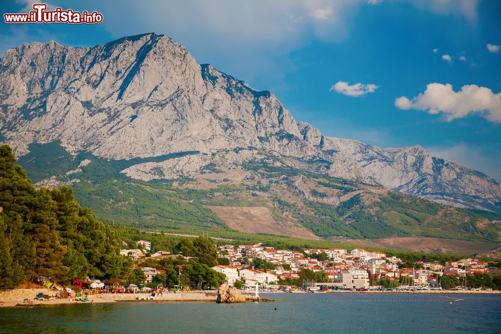 Immagine Una suggestiva veduta della costa di Baska, Croazia, con le montagne sullo sfondo. Siamo nell'estremità meridionale dell'isola di Krka. Il paese sorge in una profonda baia circondata da colline e chiusa dalla catena del monte Velebit.