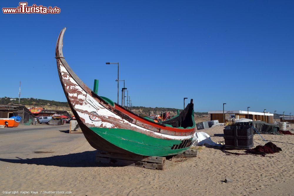 Immagine Una vecchia barca da pesca in legno sulla spiaggia di Costa da Caparica, Portogallo. In questa località dedita alla pesca si possono assaporare molti piatti a base di pesce, in particolare le caldeiradas a cui ogni anno è dedicato un festival - © Kagan Kaya / Shutterstock.com