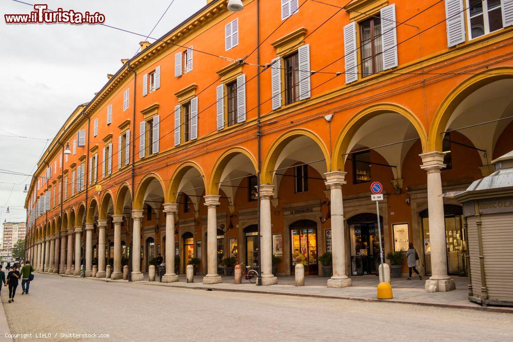 Immagine Uno scorcio del centro cittadino di Modena, Emilia-Romagna. Lo storico palazzo dalla facciata arancione è caratterizzato da un lungo porticato con negozi e attività commerciali - © LIeLO / Shutterstock.com