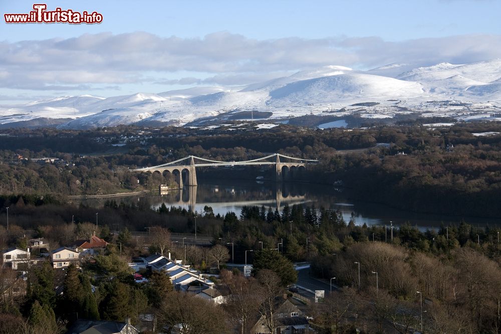 Immagine Veduta dalla Colonna Anglesey con il ponte Menai Suspension, Galles, UK. Il ponte sospeso sullo stretto di Menai collega Anglesey alla terraferma. Sullo sfondo le Snowdonian Hills coperte di neve.