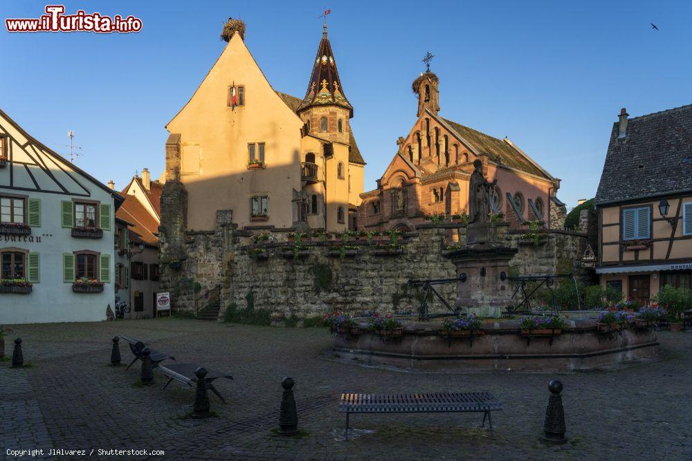 Immagine Veduta del centro storico di Eguisheim, Francia: il castello, la chiesa e la fontana di San Leone nella piazza principale  su cui si affacciano anche case a graticcio - © JlAlvarez / Shutterstock.com