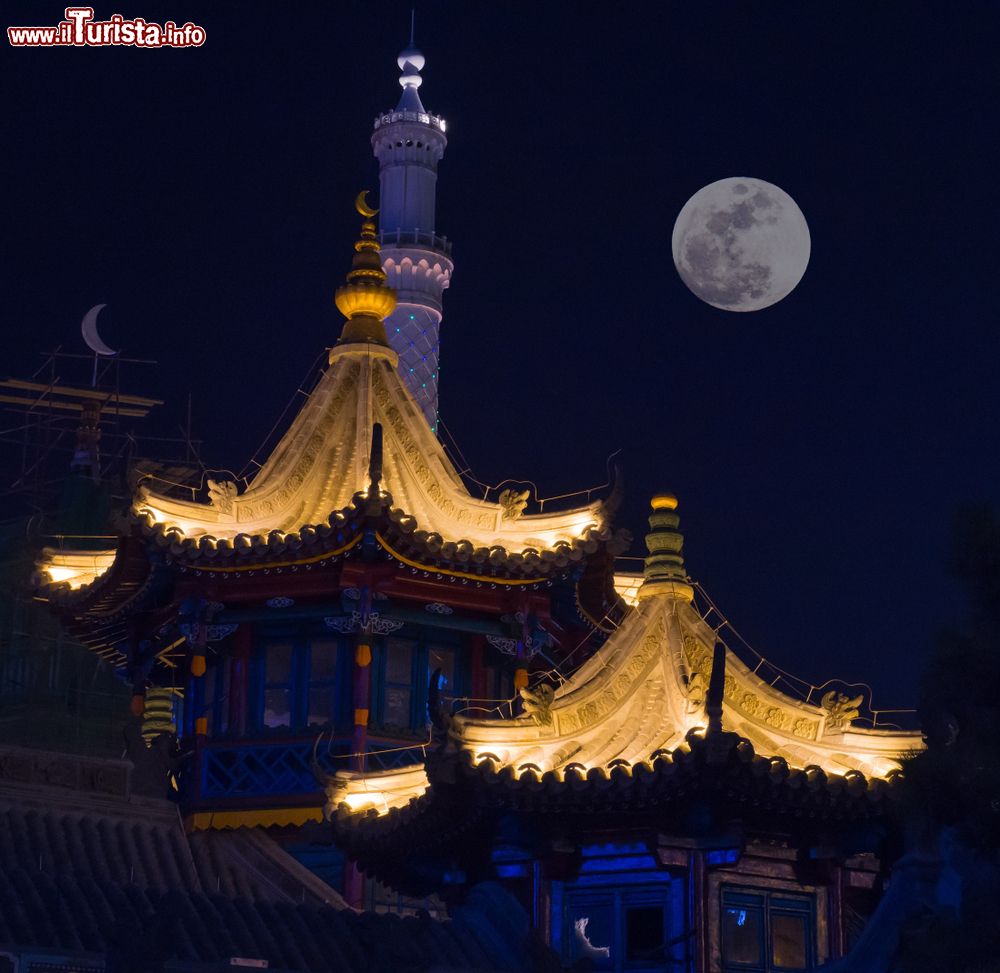 Immagine Veduta notturna di tetti in una strada islamica di Hohhot, capitale della Mongolia Interna, Cina. Sullo sfondo, una suggestiva luna piena.