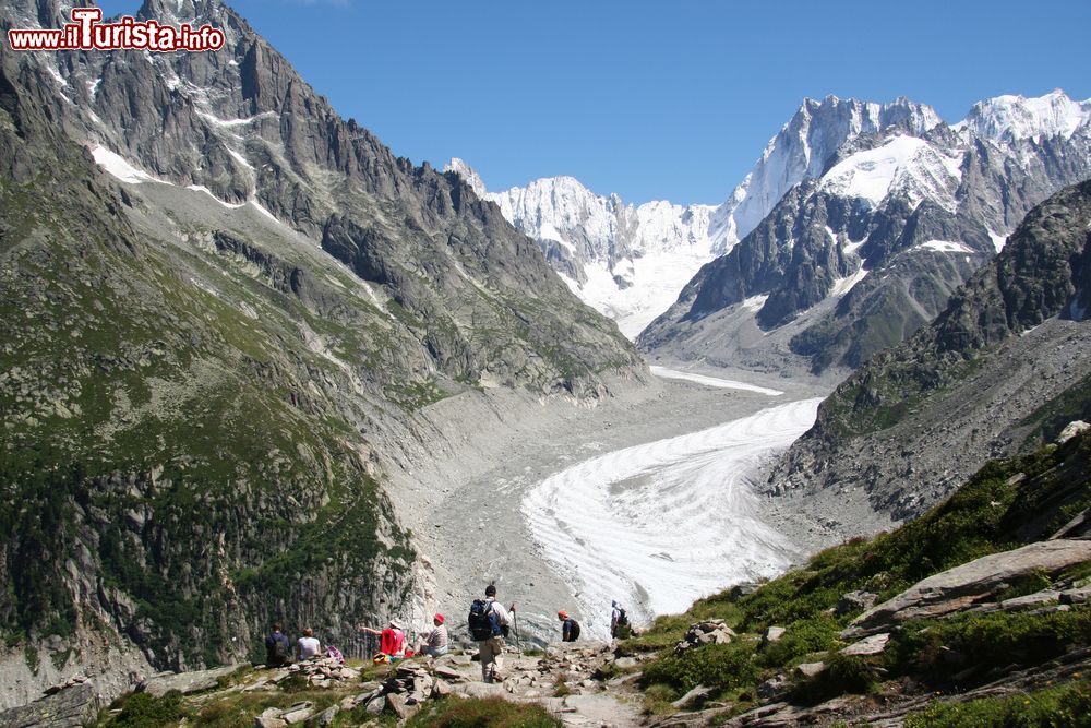 Immagine Veduta sul ghiacciaio Mer de Glace nel massiccio del Monte Bianco, Chamonix (Francia). In primo piano, un gruppo di escursionisti in cammino in una giornata estiva di sole.