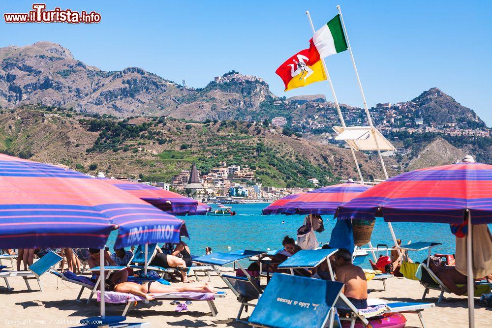 Immagine Bandiere al vento in una spiaggia di Giardini Naxos, Sicilia. Anticamente chiamata Naxos, è stata uno dei primi insediamenti greci dell'isola - © vvoe / Shutterstock.com