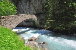 L'acqua limpida di un torrente di montagna e un antico ponte in pietra a Pré-Saint-Didier, Valle d'Aosta. Siamo nella Valdigne, l'alta valle della Dora Baltea.

