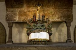 Altare in una chiesa di Goslar (Germania): la figura di Gesù scolpita nella croce sopra una copia della Bibbia aperta - © geogif / Shutterstock.com