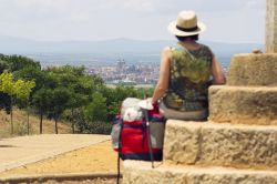 Astorga, Cammino di Santiago di Compostela: una pellegrina seduta su una croce di pietra osserva il panorama a Astorga (Spagna).

