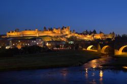 Panorama notturno di Carcassonne, sulle rive dell'Aude, nella Francia meridionale. Le fortificazioni di età romana e il Ponte Vecchio vengono illuminate in maniera molto suggestiva ...