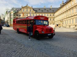 Bus turistico rosso per City Tour davanti alla Nuova Residenza di Bamberga, Germania - © cytoplasm / Shutterstock.com