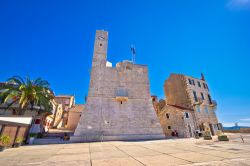 La piazza principale di Komiza (Croazia) con monumento storico e torre dell'orologio in una giornata di sole.

