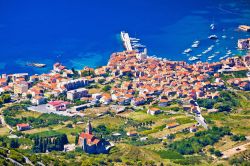 Panorama aereo della cittadina di Komiza, isola di Vis, Croazia. Questo antico borgo di pescatori si affaccia sulle acque cristalline e trasparenti del mare Adriatico.
