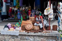 Una venditrice di souvenir nella principale via lungo il porto di Roseau, Dominica. Qui è un tripudio di colori, oggetti di artigianato locale e profumi di frutta ed erbe aromatiche - byvalet ...