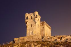 Antica torre di Tarifa illuminata di notte, Spagna. Un particolare del castello di Santa Catalina che domina dall'alto le acque delle Stretto dove venne costruito nel secondo decennio del ...