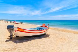 Una tradizionale barca da pesca colorata ormeggiata sulla spiaggia di sabbia a Armacao de Pera nella regione dell'Algarve, Portogallo.
