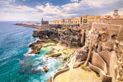 Un tratto delle mura fortificate di Melilla, Spagna: sullo sfondo della costa rocciosa, il faro e il porto cittadino di questa enclave in territorio marocchino.

