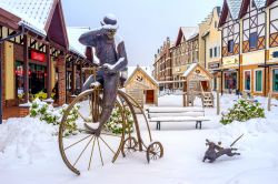 Una simpatica statua nell'area commerciale olandese di Kiev, Ucraina. La scultura in bronzo di un bassotto corre accanto a un uomo in bicicletta - © eFesenko / Shutterstock.com