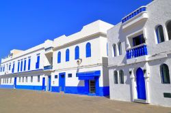 Una strada di Asilah fotografata con il sole, Marocco. A risplendere sono il cielo azzurro e i particolari blu delle facciate delle abitazioni.
